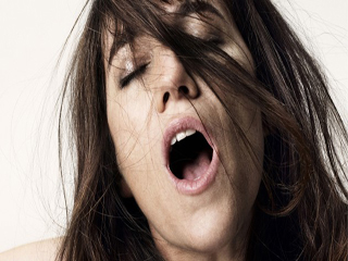 Orgasme féminin, une femme jouit la bouche ouverte, les cheveux ébouriffées. 